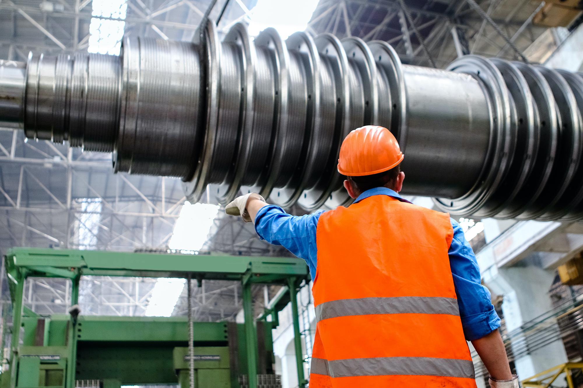 A factory employee pointing at a drill bit